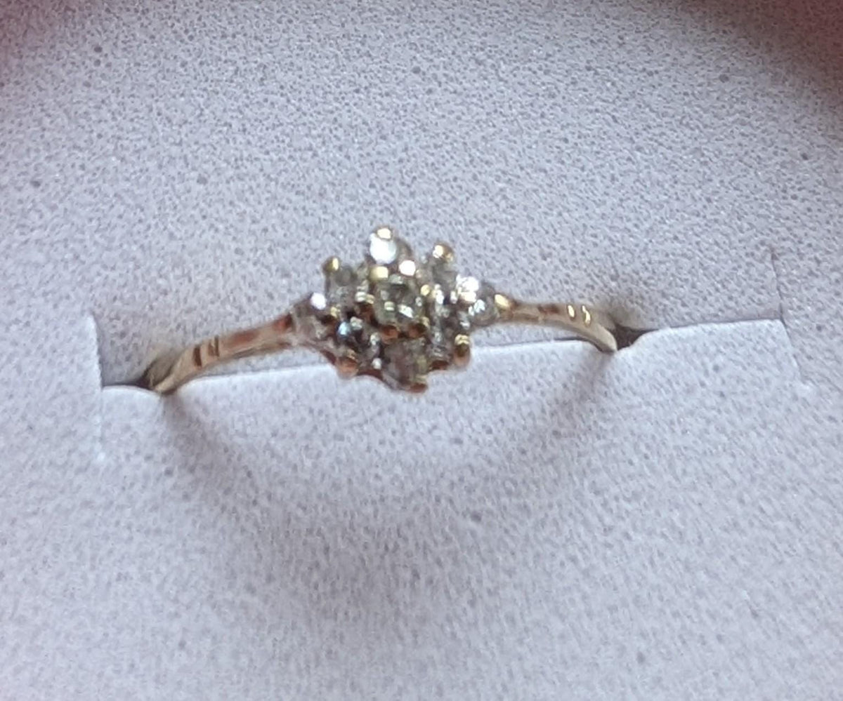 A gold ring featuring a cluster of small, clear gemstones. The ring's band is slender, and the gemstones are arranged in a floral or starburst design. The ring is set against a white background, suggesting a presentation box. __etsy:7692670460